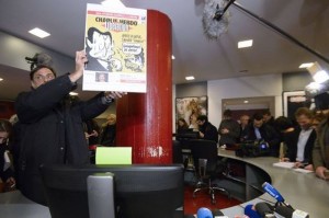 A man holds the cover of a November 2011 issue of French newspaper Liberation bearing the name of satirical weekly Charlie Hebdo made after the bombing of Charlie Hebdo's offices on January 9, 2015 at Liberation's offices in Paris as editorial staff of Charlie Hebdo and Liberation gather following the deadly attack that occurred on January 7 by armed gunmen on the Paris offices of Charlie Hebdo. AFP PHOTO / BERTRAND GUAY