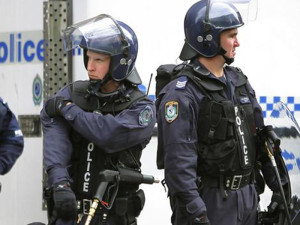 Riot police watch demonstrators protest against the Asia-Pacific Economic Co-operation (APEC) summit from a distance in Sydney