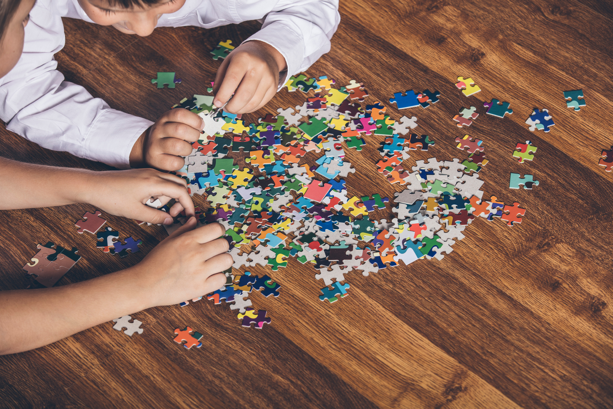 Happy boy and girl collect puzzle lying on the floor
