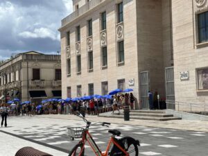 visitatori in fila al museo con ombrelli per proteggersi dal sole