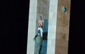 Uomo sale sulla statua della dea Athena