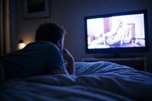 uomo guarda la tv dal letto