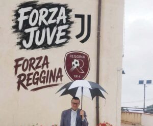 don zampaglione sotto la pioggia protetto dall'ombrello della juve