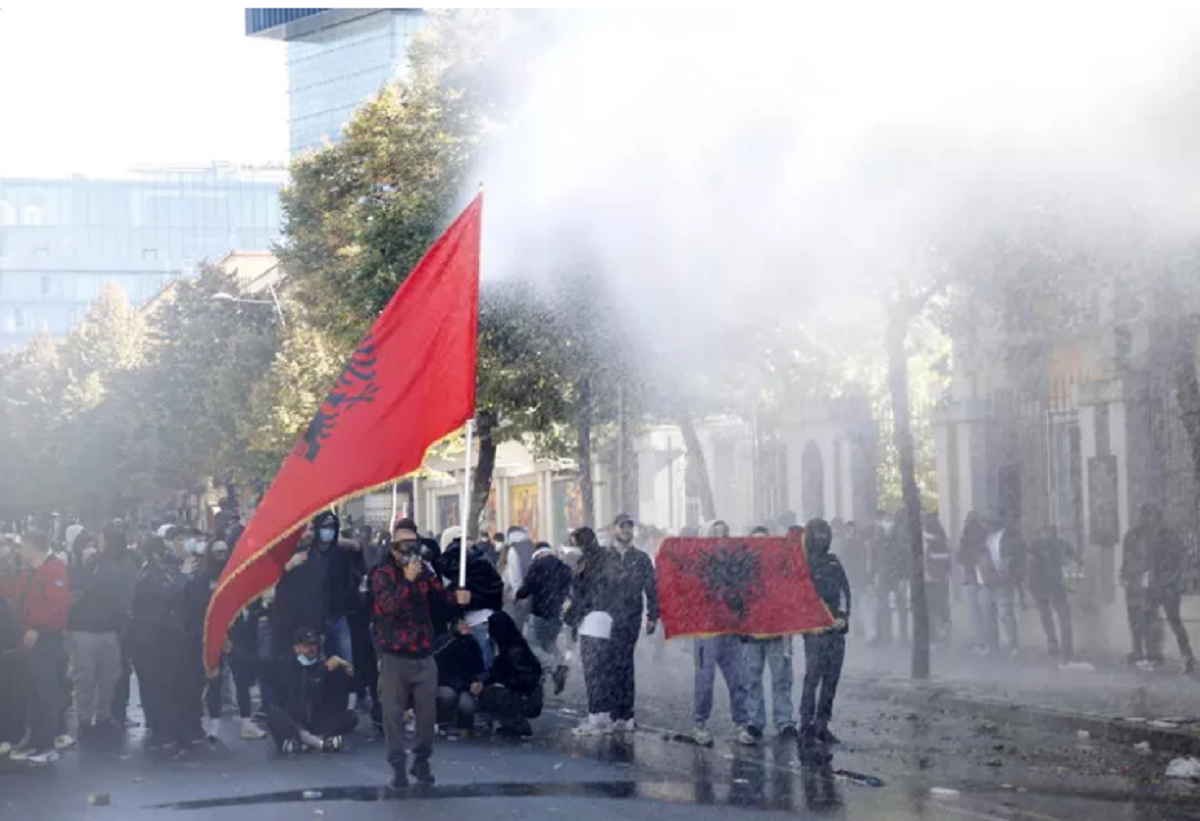 Manifestanti con bandiere albanesi tra fumo e getti d’acqua, fotografia pubblicata da StrettoWeb